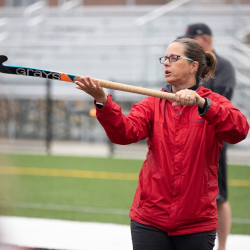 photo of a michigan coach showing players how to hold a field hockey stick